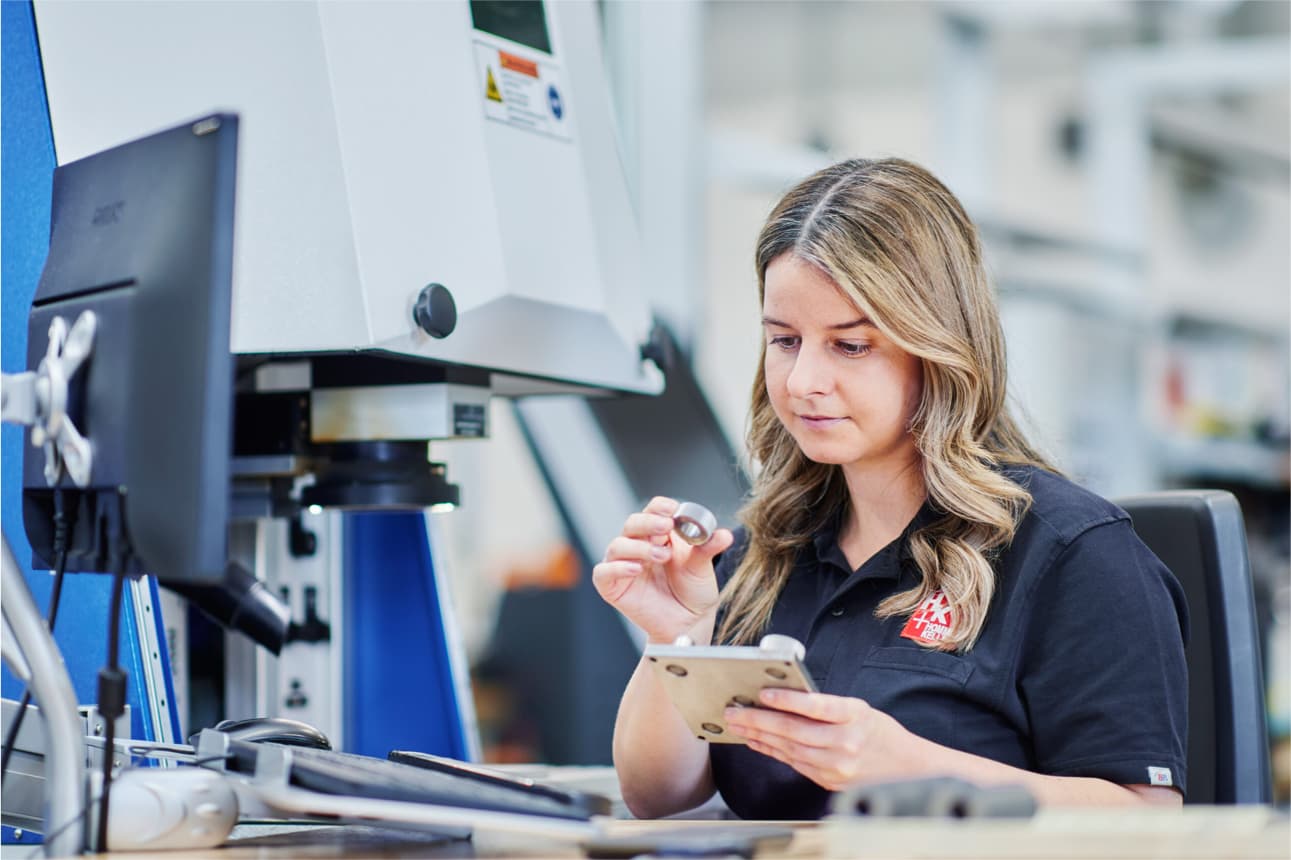 Mitarbeiterin prüft ein graviertes Metallteil im Produktionsbereich von Hommel+Keller